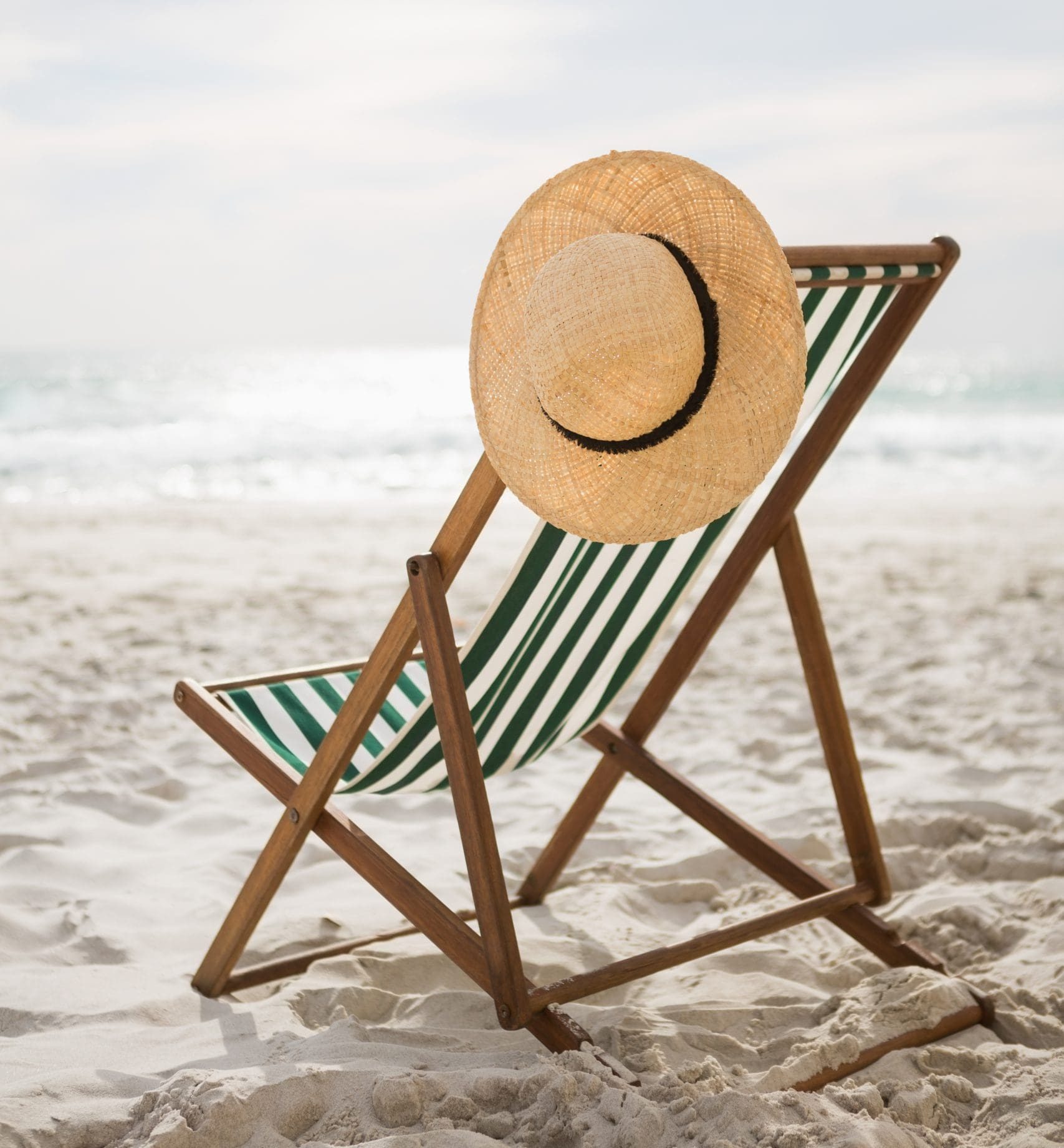 Straw hat kept on empty beach chair at tropical sand beach